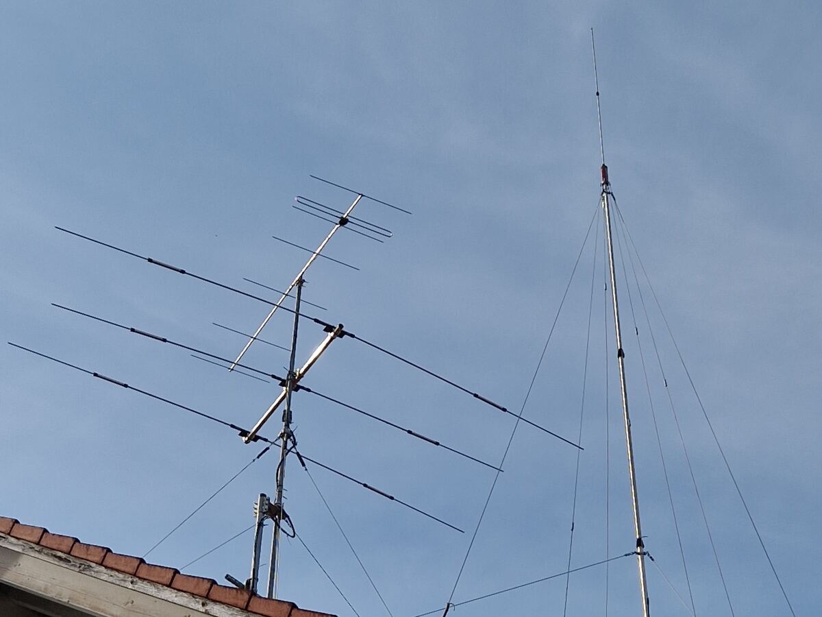 Mehrelement-Kurzwellen-Yagi und Vertikalantenne mit Abspannungen auf dem Hausdach von DL3MXX vor blauem Himmel