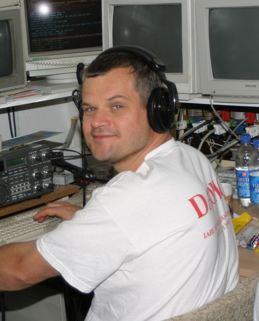 Olaf, DL3MXX, mit Kopfhörer am Contest-Arbeitsplatz vor Transceiver, Tastatur und mehreren Bildschirmen